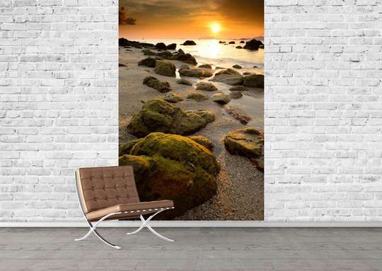 Wall Mural with a beautiful sunset and rocks on the shore.